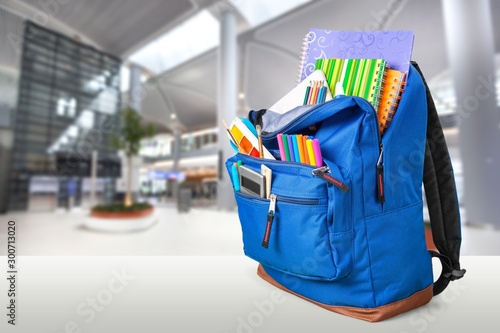 Colorful school supplies in backpack on blurred background
