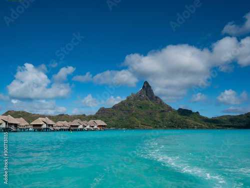 Luxury overwater villas on blue lagoon, white sandy beach and Otemanu mountain at Bora Bora island, Tahiti, French Polynesia.