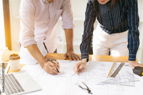 Two architects or engineers  working on blueprint plans with a laptop and pencil in office. Team Architect or engineers  working on architects project. working table.