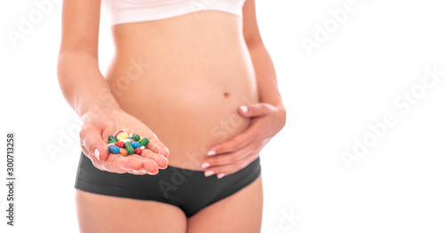Pregnant woman shows pills on a white.
