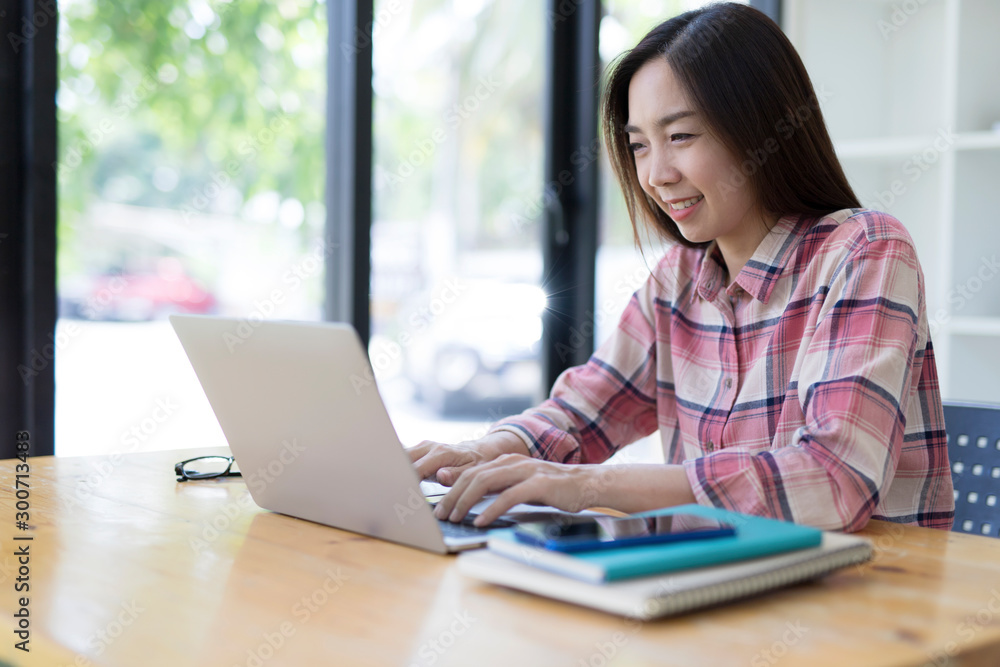 Portrait of a young business woman using laptop computer while working. Young asian business woman working with laptop in coffee shop cafe. Portrait of a young business woman using laptop computer while working. Young asian business woman working with laptop in coffee shop cafe.
