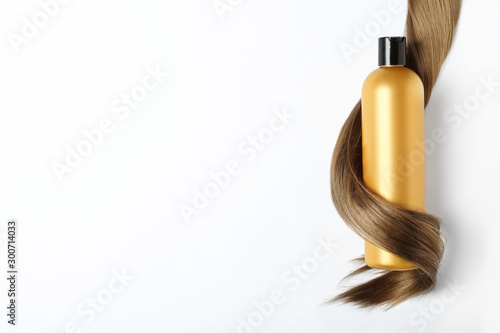 Shampoo bottle wrapped in lock of hair isolated on white, top view. Natural cosmetic products photo