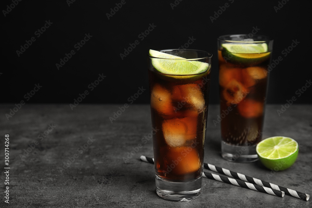 Refreshing soda drinks with straws on grey table against black background, space for text Refreshing soda drinks with straws on grey table against black background, space for text