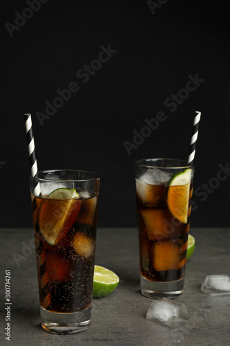 Refreshing soda drinks with straws on grey table against black background, space for text