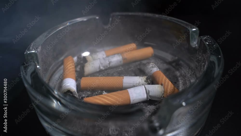 Throw a cigarette butt into an ashtray on a black background.Slow motion Throw a cigarette butt into an ashtray on a black background.Slow motion
