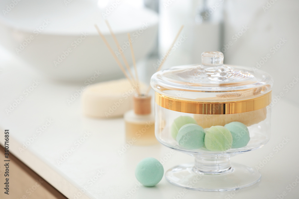 Jar with bath bombs and loofah sponge on white countertop in bathroom Jar with bath bombs and loofah sponge on white countertop in bathroom