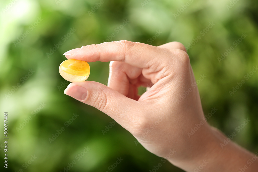 Woman holding beautiful honey agate gemstone on blurred green background, closeup Woman holding beautiful honey agate gemstone on blurred green background, closeup