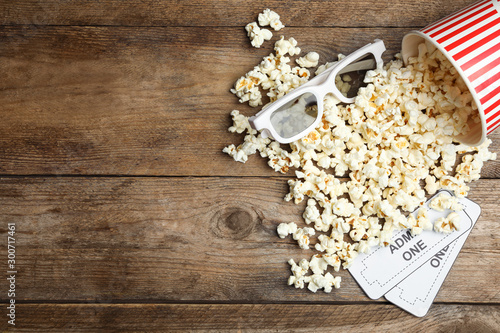 Popcorn, cinema tickets and 3d glasses on wooden background, flat lay. Space for text