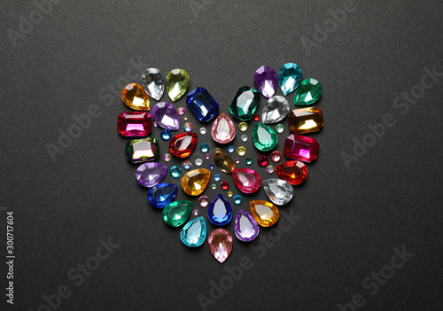 Heart made of beautiful gemstones on dark background, flat lay