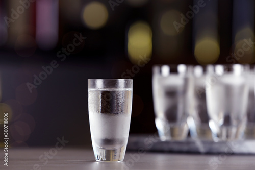 Fototapeta Shot of vodka on table against blurred background