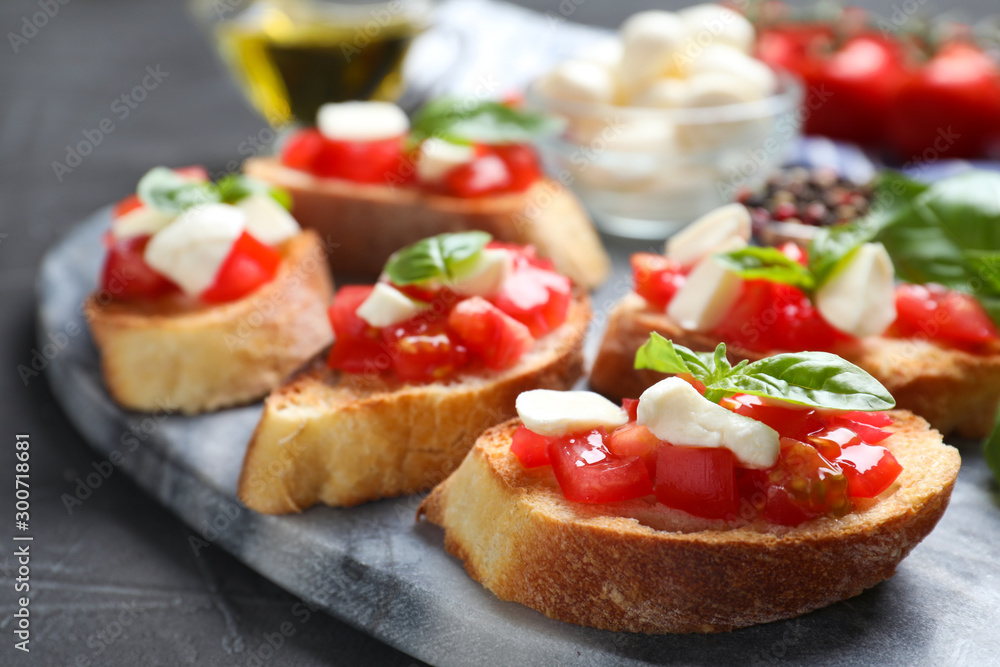 Delicious bruschettas with cheese and tomatoes on grey table, closeup