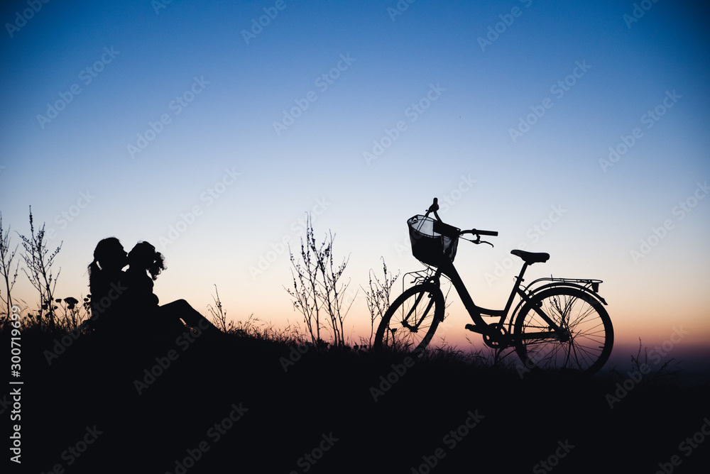 Silhouette of mother and baby biking at sunset
