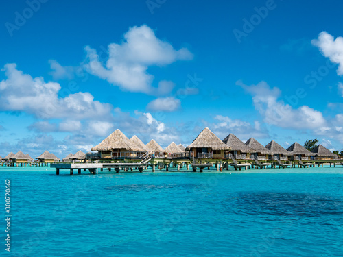 Sailing a boat around blue lagoon and luxury overwater villas at Bora Bora island  Tahiti  French Polynesia