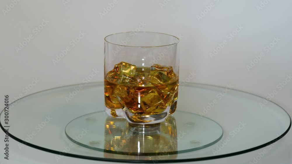 Beautifu view of rotating glass of whiskey with ice cubes. Alcohol and health concept. Beautifu view of rotating glass of whiskey with ice cubes. Alcohol and health concept.