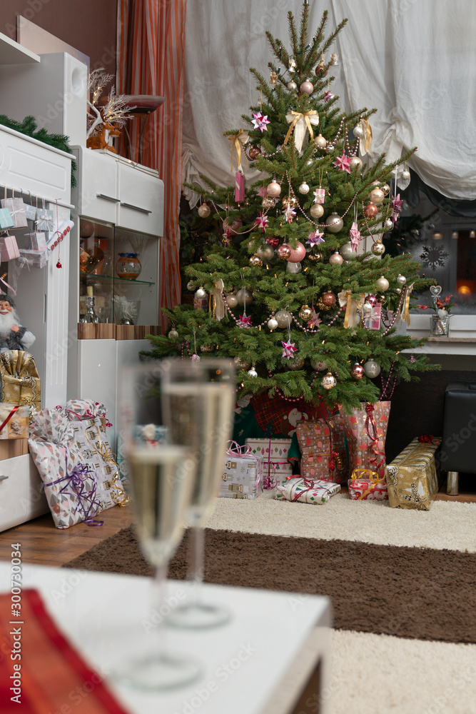 Φωτογραφία It is holy night, the decorated Christmas tree is in the living room and below are the wrapped Christmas presents