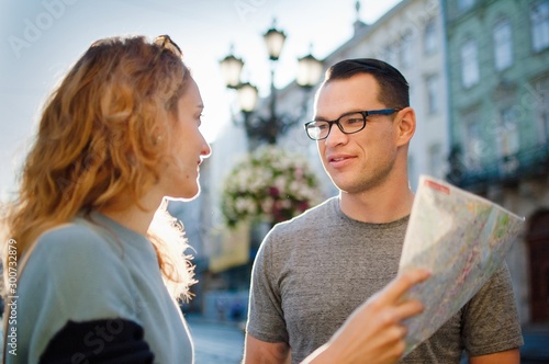 Young couple watching the city map and searching for direction early in the morning on empty ancient square somewhere in Europe