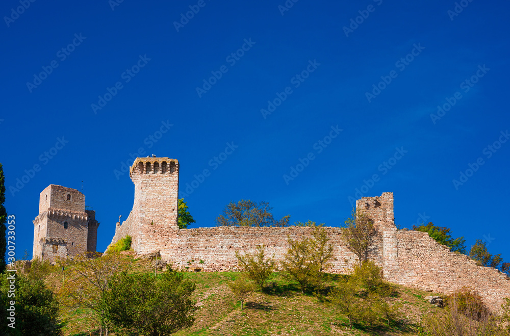 Assisi ancient medieval walls ruins at the top of the town with blue sky above
