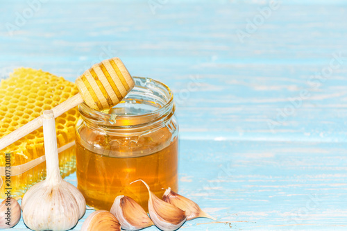 Honey and pieces of garlic on the background of honeycomb. Honey in a glass jar and honeycomb. photo