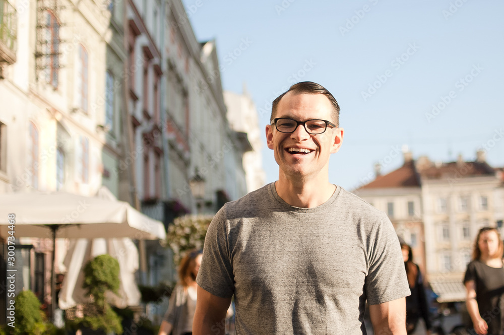 Half body shot of young man in a street of an old town in Europe looking in the camera with brown eyes and eyesglasses Half body shot of young man in a street of an old town in Europe looking in the camera with brown eyes and eyesglasses