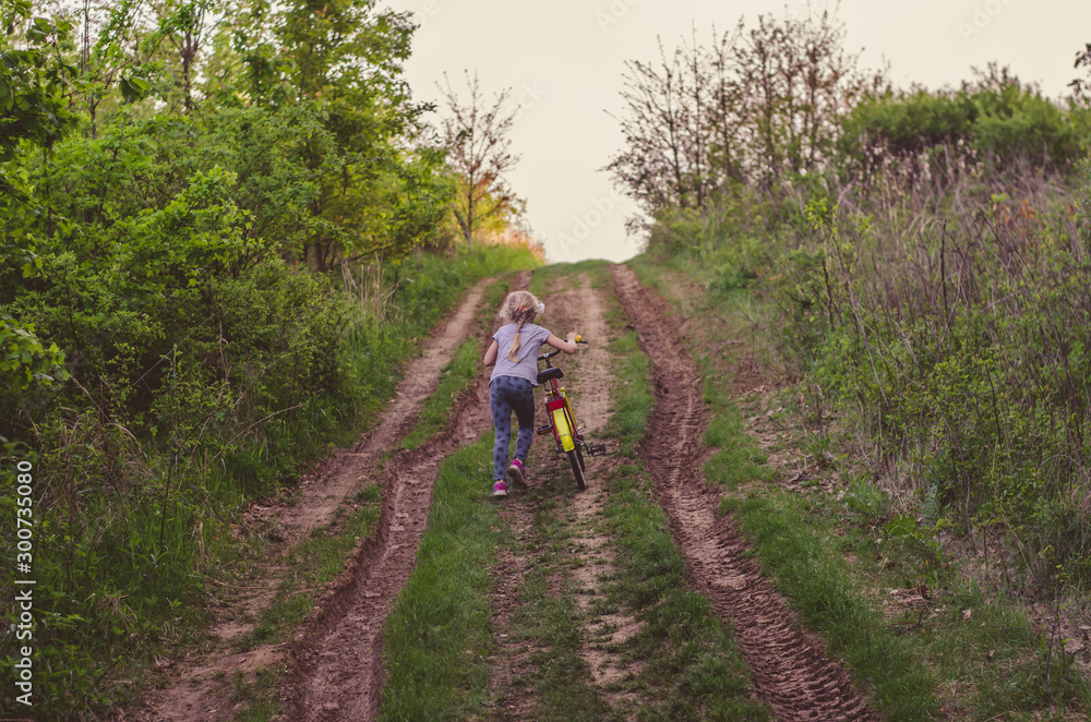 little child pushing bicycleup to hill in the rural path little child pushing bicycleup to hill in the rural path