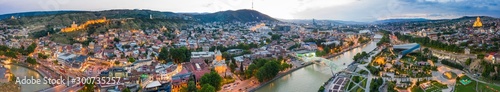 The evening panorama of the old town on Sololaki hill, crowned with Narikala fortress, the Kura river reflects the evening city lights and cars traffic with blure in Tbilisi, Georgia
