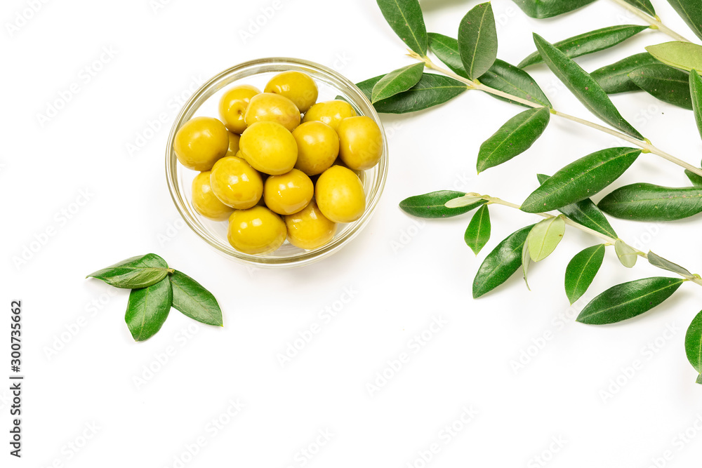 Some fresh canned olives in a glass bowl with olive leaves on the white background. Some fresh canned olives in a glass bowl with olive leaves on the white background.
