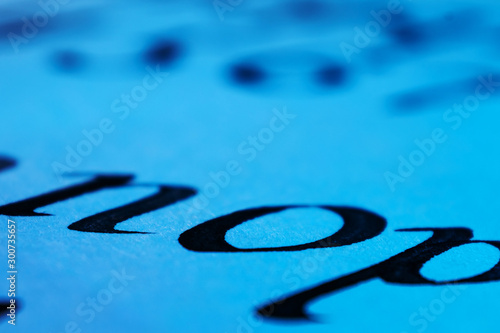 The letters of the English alphabet are written in ink and pen. Vintage freehand writing concept. Macro photo of letters. Calligraphy training. Bluish light.