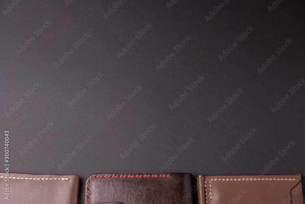 leather wallets on a black background with space for an inscription. Leather craft concept. - obrazy, fototapety, plakaty 