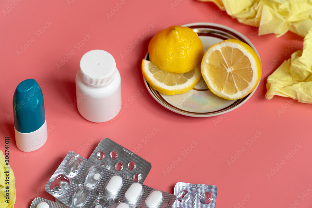concept of cold: sliced lemon with cold pills and nasal spray on pink background concept of cold: sliced lemon with cold pills and nasal spray on pink background