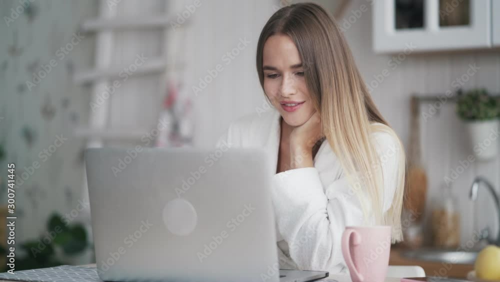 Young woman uses laptop for work at home, looks at screen of computer Young woman uses laptop for work at home, looks at screen of computer