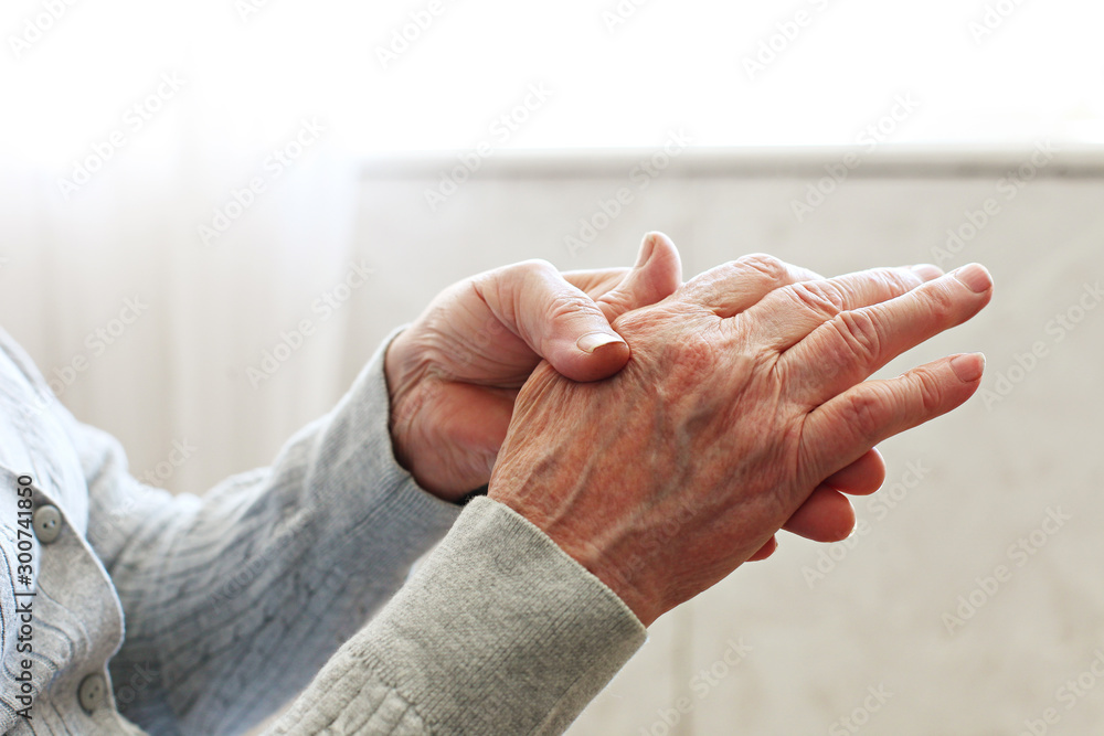 Elderly woman applying moisturizing lotion cream on hand palm, easing aches. Senior old lady experiencing severe arthritis rheumatics pains, massaging, warming up arm. Close up, copy space, background - obrazy, fototapety, plakaty 