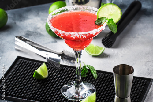 Watermelon margarita, alcoholic cocktail with silver tequila, lime juice, mint, watermelon and crushed ice, metal bar tools, gray background photo