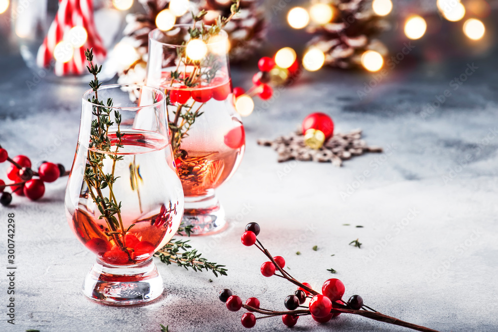 Winter alcoholic cocktail with red berries, liquor, gin, thyme and vodka for Christmas or New Year. Holiday table setting - obrazy, fototapety, plakaty 