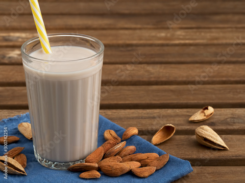 Almond milk with almonds on a wooden table. Close-up. Healthy eating concept. Copy space. Natural light. photo