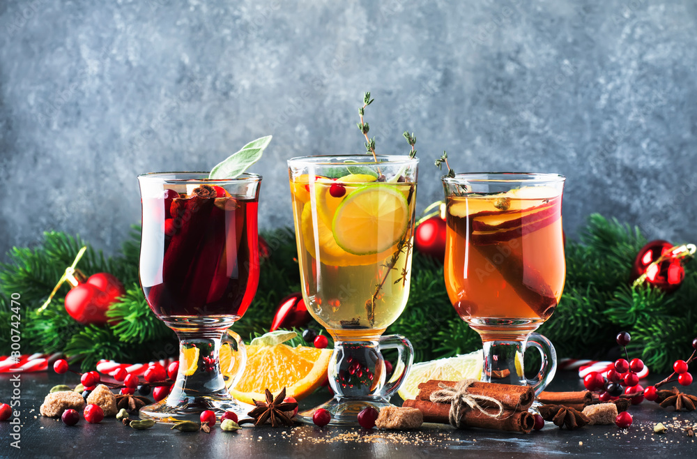 Mulled wine and mulled cider. Hot winter drinks and cocktails for christmas or new year's eve in glass mugs with spices and citrus fruit - obrazy, fototapety, plakaty 