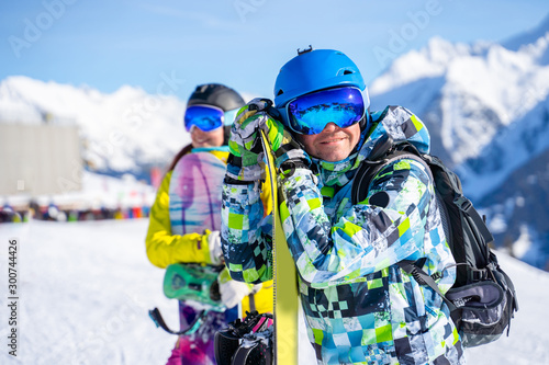 Athlete man and woman snowboarders standing on snow resort against backdrop of mountain.