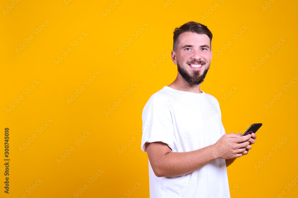 Young handsome man with facial hair posing yellow gray wall with a lot of copy space for text. Portrait of confident bearded male, wearing blank white oversized t-shirt. Isolated, background. Young handsome man with facial hair posing yellow gray wall with a lot of copy space for text. Portrait of confident bearded male, wearing blank white oversized t-shirt. Isolated, background.