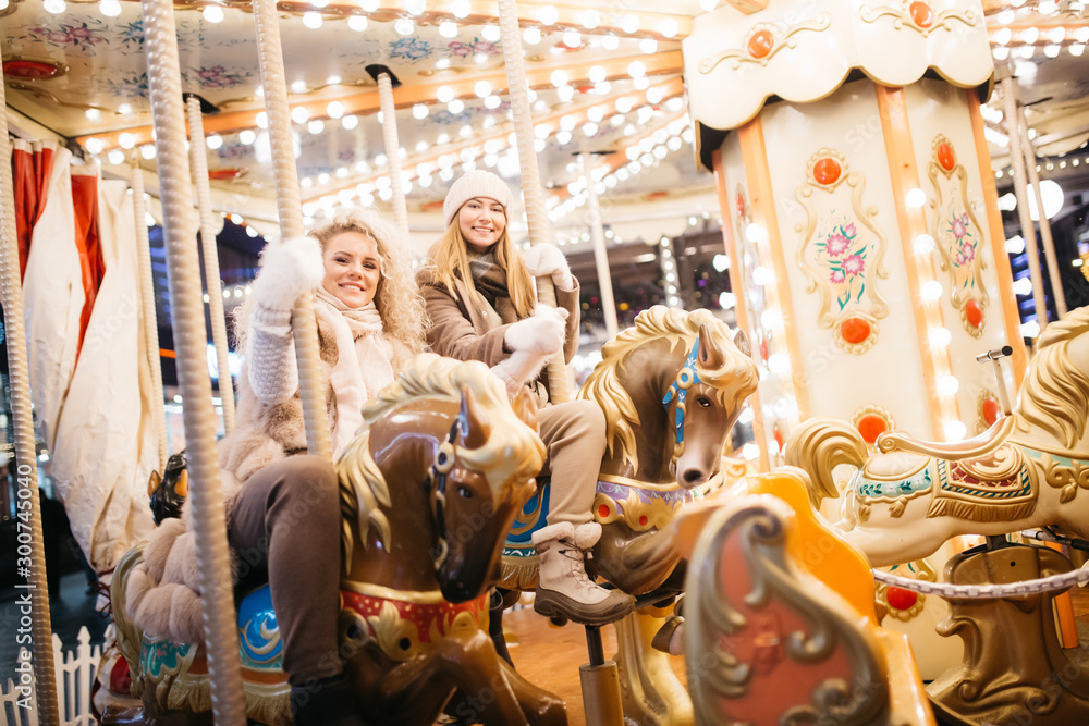 Photo of two women riding on carousel in park