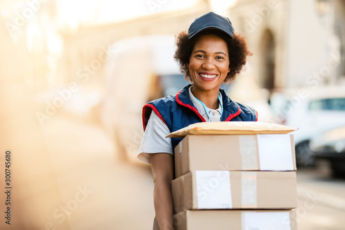 Portrait of happy African American deliverer with packages. photo