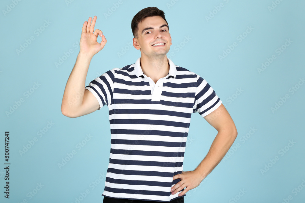 Young man showing gesture OK on blue background Young man showing gesture OK on blue background