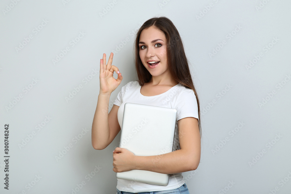 Young girl with laptop computer on grey background Young girl with laptop computer on grey background