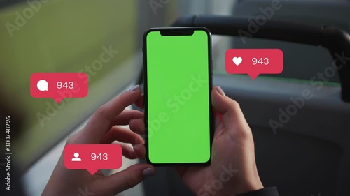 Close up of a woman's hand holding a mobile telephone with a vertical green screen in tram chroma key smartphone technology. Animation with User Interface - Likes, Followers, Comments for Social Media photo