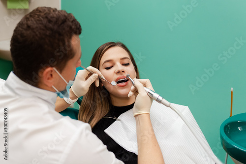 Dentist performs professional polishing of tooth enamel for woman patient 