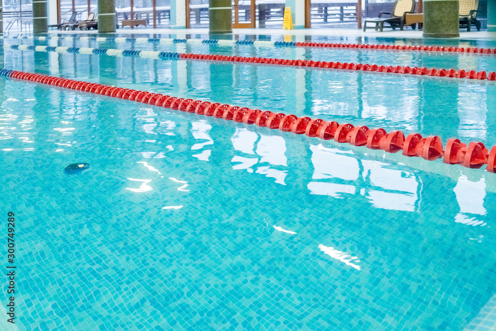 Community swimming pool with racing lanes.Swimming pool with marked red and white lanes. Empty swimming pool without people with quiet standing water. Water sports in indoor pool.