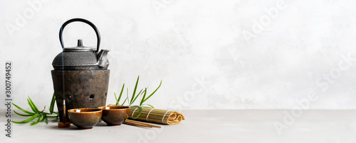 Simple still life with tea set, scattered tea, bamboo Mat, sticks, incense. Asian background with space for text. photo