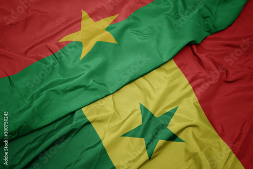 waving colorful flag of senegal and national flag of burkina faso.