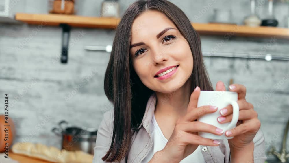 Beautiful young morning girl posing with white cup of coffee in kitchen at home close-up Beautiful young morning girl posing with white cup of coffee in kitchen at home close-up