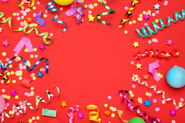 Colorful ribbons with paper stars and confetti on red background