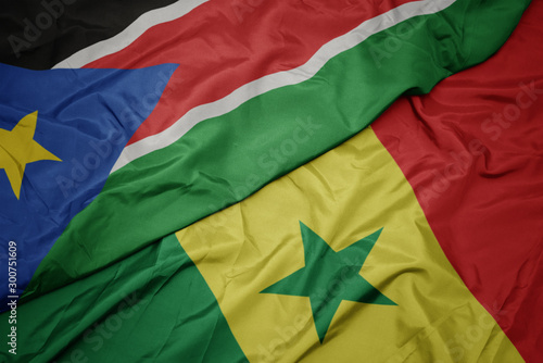 waving colorful flag of senegal and national flag of south sudan.
