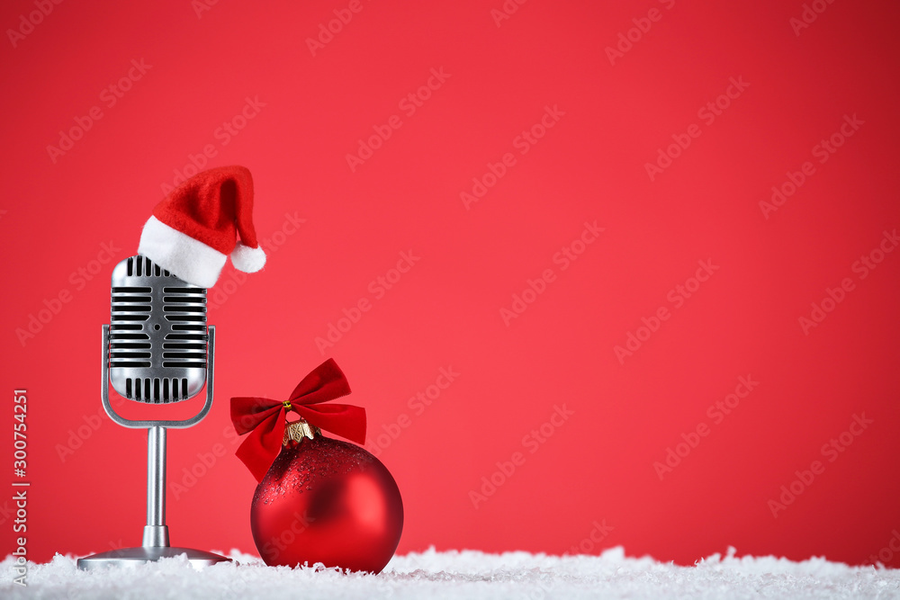 Retro microphone with santa hat and bauble on red background - obrazy, fototapety, plakaty 